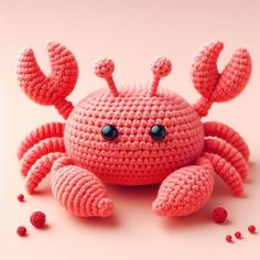 a crocheted crab sitting on top of a pink surface