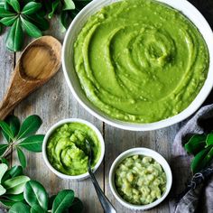 guacamole in a white bowl surrounded by two small bowls and spoons