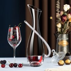 a glass pitcher and vase filled with cherries on a table next to other items