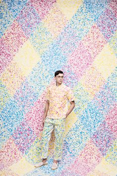 a man standing in front of a multicolored wall with sprinkles on it