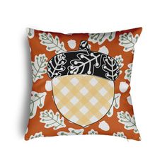 an orange pillow with a black and white design on the front, featuring leaves and acorns