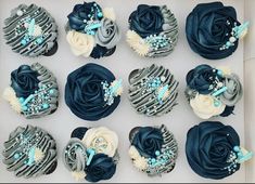 twelve cupcakes with blue and white frosting in a box, decorated with flowers