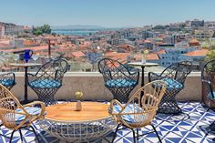 an outdoor patio with wicker chairs and tables overlooking the city