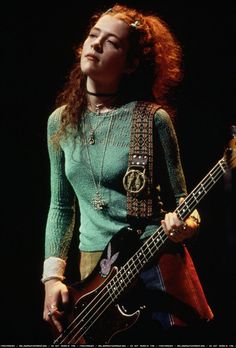 a woman holding a bass guitar on stage