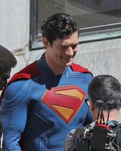 a man dressed as superman is surrounded by reporters