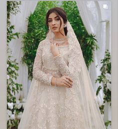 a woman in a wedding dress standing with her hands on her chest and wearing a veil