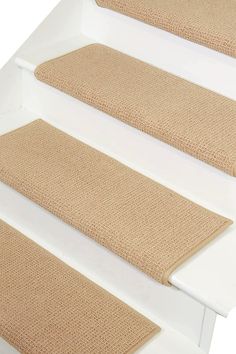 three beige stair mats on the bottom of a set of stairs