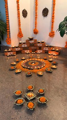 there are many candles on the floor in front of each other with orange decorations around them