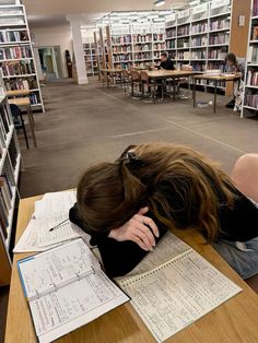 a person sleeping on top of a table in a library