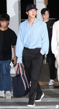 a man in a blue shirt and black pants is walking with his hand on his hip