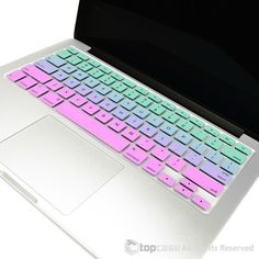 an open laptop computer sitting on top of a white table with pink and green keys