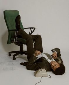 a man laying on the ground with headphones in his ears, next to an office chair