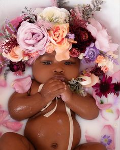 a baby in a tub with flowers on it's head and hands around its body