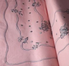 a pink bed spread with flowers and vines on it, laying next to a pillow