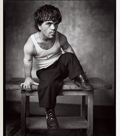 a man sitting on top of a wooden bench in front of a black and white photo