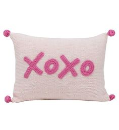 a pink pillow with the word xo on it and pom - poms