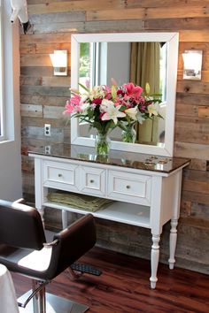 a white vanity with flowers on it in front of a mirror