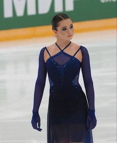 a female figure skating on the ice in a black dress with sheer sleeves and an open back