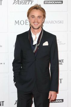 a man in a suit and tie standing on a red carpet