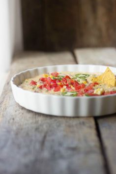 a white dish filled with salsa and tortilla chips on top of a wooden table