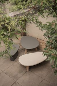 two round tables sitting next to each other on top of a tiled floor covered in trees