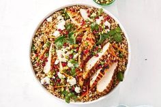 a white bowl filled with chicken, rice and veggies on top of a table