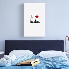 a bed with a blue comforter and a red heart on the wall above it