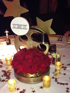 a table topped with red roses and gold stars next to an old movie projector