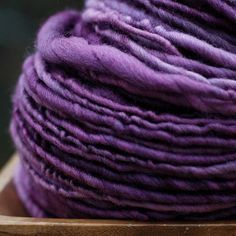 a skein of purple yarn sitting on top of a wooden box