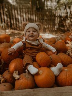 a baby sitting in a pile of pumpkins