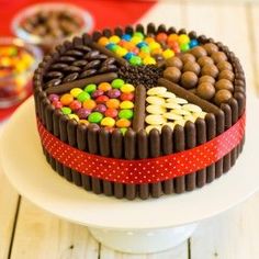 a heart shaped chocolate cake decorated with candy and candies on a white plate next to other desserts