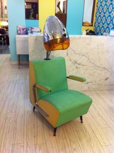 a green chair sitting on top of a hard wood floor next to a marble counter