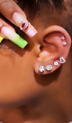 a close up of a person with ear piercings on their ears and one hand holding a pair of scissors