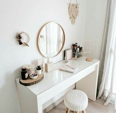 a white desk with a mirror, stool and other items on it in front of a window