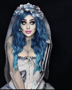 a woman with blue hair and makeup wearing a veil