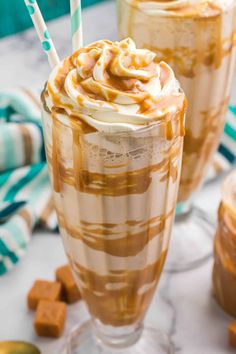 two glasses filled with caramel milkshake and topped with whipped cream