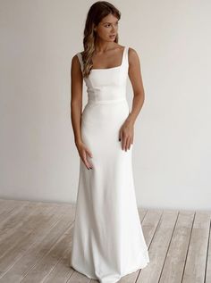 a woman in a white dress standing on a wooden floor