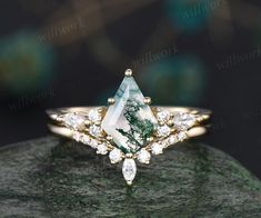 a green and white diamond ring on top of a rock with diamonds around the band