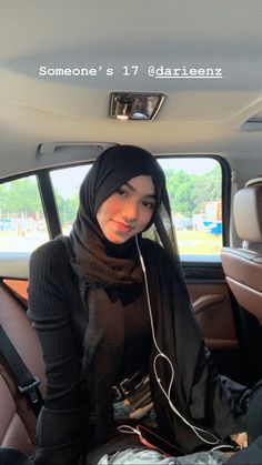 a young woman sitting in the back seat of a car listening to music on headphones