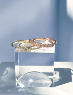 two gold wedding rings sitting on top of a clear box