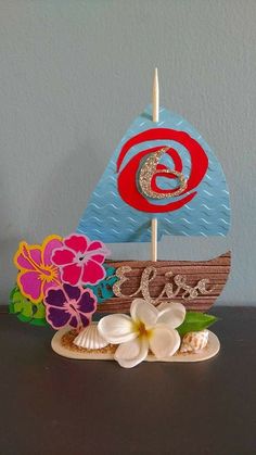 a cake topper with a sailboat on it and flowers in the foreground