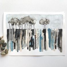 an abstract painting with trees and rocks on the ground next to it, in front of a white wall