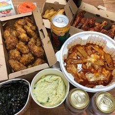 an assortment of food and drinks sitting on a table next to cans of sodas