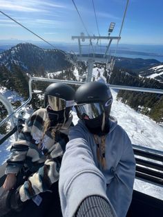 two people on a ski lift wearing helmets