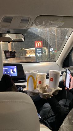 a man sitting in the back seat of a car while holding up a cell phone