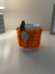 an orange knitted cup cozy sitting on top of a table