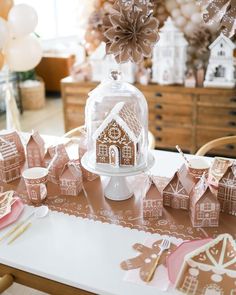 a table with gingerbread houses on it and some balloons in the air behind them