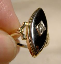 A 10k black Alaskan diamond cabochon hematite ring with a diamond from the 1960s.  This size 5-1/4 yellow gold ring has an unusual cabochon style hematite gemstone rather than the typical faceted ones, and it has a single point clear diamond in white gold in the centre.  The bezel setting measures 7/8 x 3/8", this ring weighs 2.4 grams and it is marked 10K with a maker's mark.  It is in excellent condition with no chips, cracks, dents, bends, corrosion, damage or repairs.  Items have signs of us Retro Formal Rings With Polished Finish, Retro Rings With Polished Finish For Formal Occasions, Retro Polished Rings For Formal Events, Vintage Diamond Cabochon Rings, Vintage Diamond Rings With Cabochon, Retro Oval Cabochon Jewelry, Vintage Oval Diamond Ring With Polished Finish, Gold Marquise Cut Collectible Jewelry, Collectible Marquise Cut Gold Jewelry