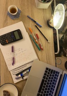 an open laptop computer sitting on top of a wooden desk next to a cup of coffee