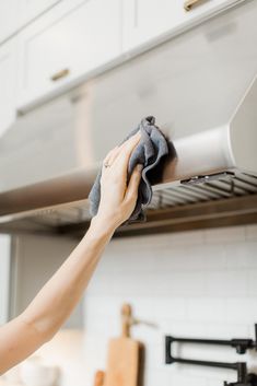 a woman is cleaning the stove with a cloth